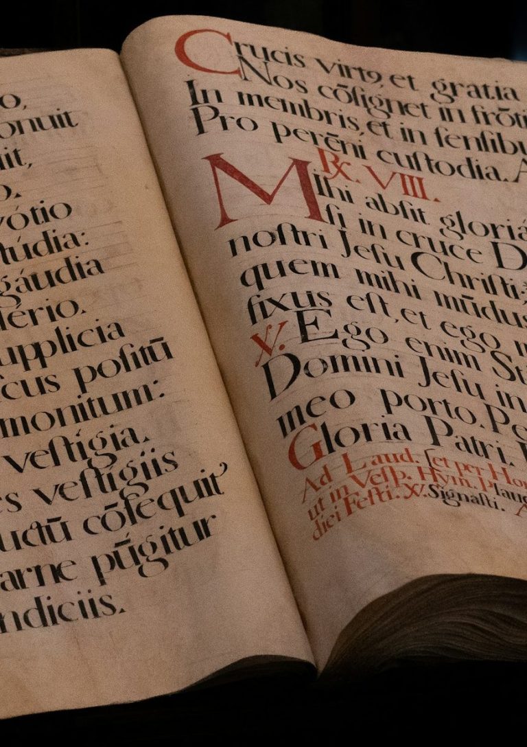 Pagine di un manoscritto medievale aperto con capilettera miniati, la ricerca storica dietro il romanzo Il Codice della Torre